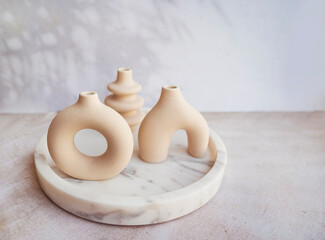 Modern beige ceramic small vases in marble tray  . Scandinavian interior style 