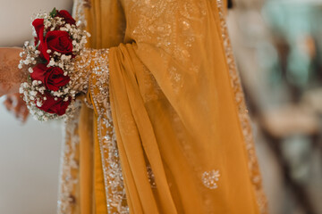 Close-Up of Traditional Yellow Bridal Attire with Red Rose Floral Details for Cultural Wedding