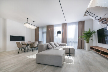 Elegant living room, decorated in pastel colors, with a fireplace and stylish furniture. .Stairs with glass railings.