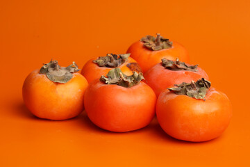 fresh persimmons on orange background 