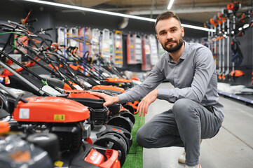 Young man buys a new lawnmower in a garden supplies store