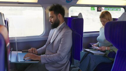 Two dedicated professionals effectively demonstrate how productivity can be maintained while traveling on a train, showcasing the inventive concept of being able to work on the go despite the commute