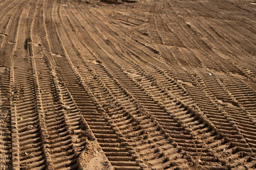 photo Close-up of vehicle tire tracks on sandy surface showcasing detailed texture and pattern in...
