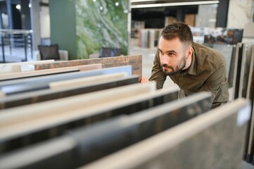 Man choosing tile among different samples in store