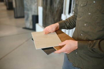 Man choosing tile among different samples in store
