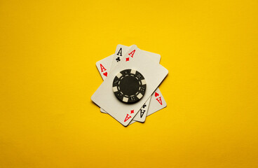 Three aces or a poker combination of three of a kind or set lie on a yellow table with one chip. The atmosphere is charged with winning excitement and poker strategy