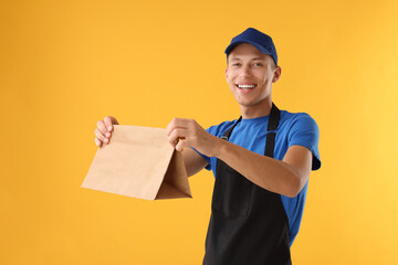 Fast-food worker with paper bag on orange background
