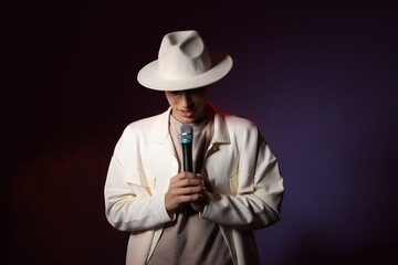 Talented young man singing on dark background