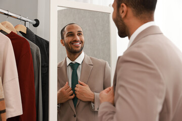 Smiling man looking at mirror at home