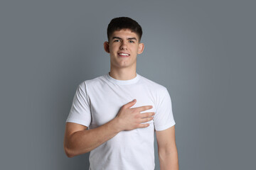 Man making promise on grey background. Oath gesture