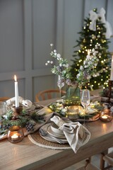 Christmas place setting with festive decor on wooden table in room