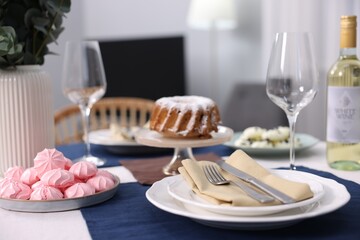 Festive table setting with dishware, desserts, wine and glasses indoors, closeup