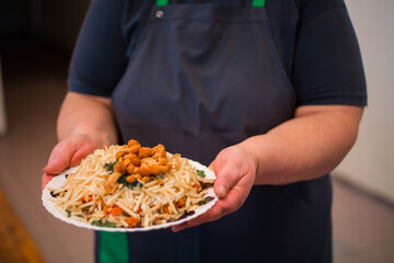 Person Holding a Plate of Food with Mushrooms and Herbs Indoors