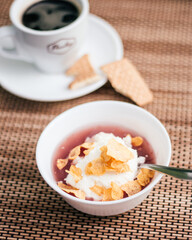 Bowl of Dessert with Yogurt, Cornflakes, and Coffee in Background