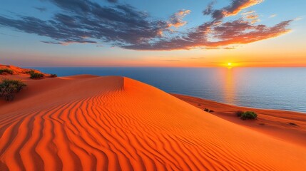 Naklejka premium Sunset over red sand dunes meeting ocean.