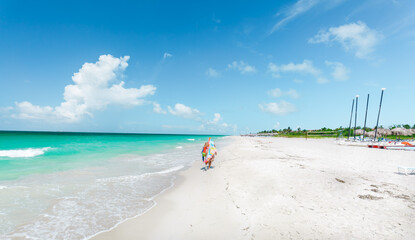 Cuba,Varadero beach,beautiful inviting gorgeous view of the ocean shore and a person walking along the beach in colorful clothing on sunny gorgeous day 