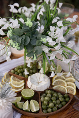 A wooden platter with a selection of appetizers &mdash; including lemon, lime, cheese, gooseberry, and berries.
