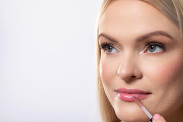 A closeup view of a woman applying lip gloss to achieve a glamorous and stunning look