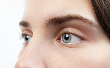 Naklejka premium Closeup view of young woman with beautiful blue eyes on white background