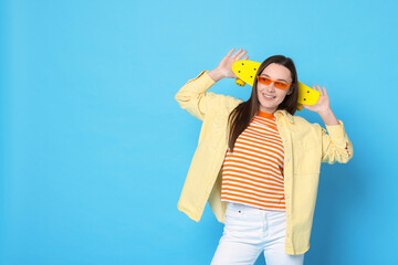 Smiling woman with penny board on light blue background. Space for text