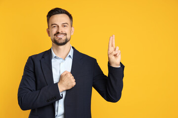 Man showing oath gesture on orange background, space for text. Making promise