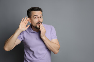 Man showing hand to ear gesture on grey background, space for text