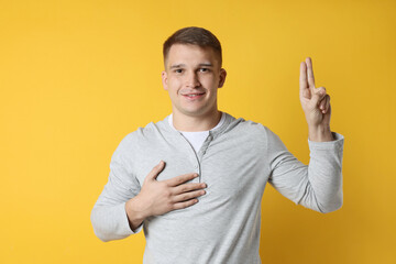 Man showing oath gesture on orange background. Making promise