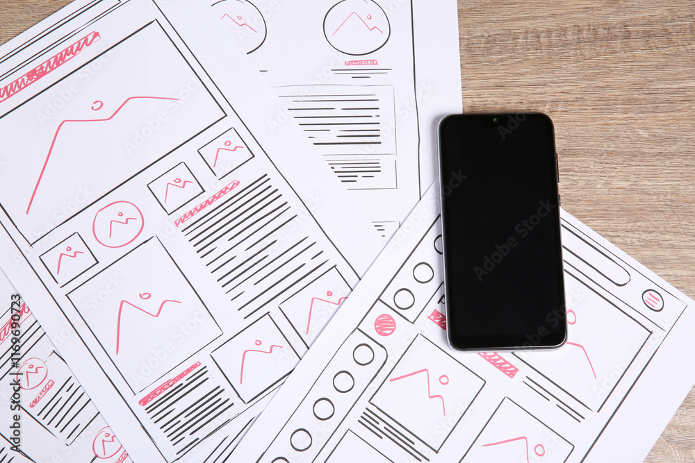 Wall mural developing ui design. sketches of website wireframes and smartphone on wooden table, top view