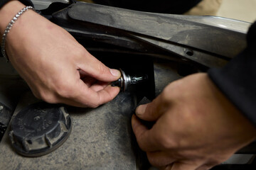 Hands skillfully holding car headlight bulbs in order to carry out a replacement task