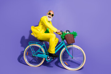 Photo of cheerful glad optimistic senior man dressed yellow trendy clothes riding bicycle isolated...