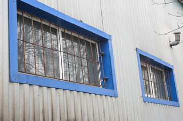 corrugated metal building blue-framed windows protected iron bars functional warehouse workshop industrial facility industrial commercial architecture building security solutions property security 