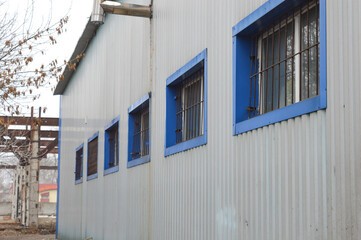 corrugated metal building blue-framed windows protected iron bars functional warehouse workshop industrial facility industrial commercial architecture building security solutions property security 