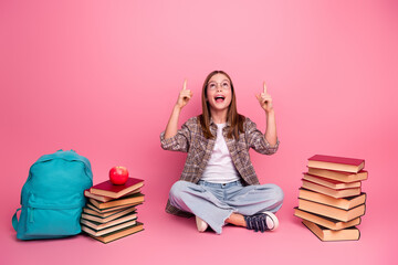 Young girl enjoying learning experience surrounded by books and school accessories with a cheerful attitude