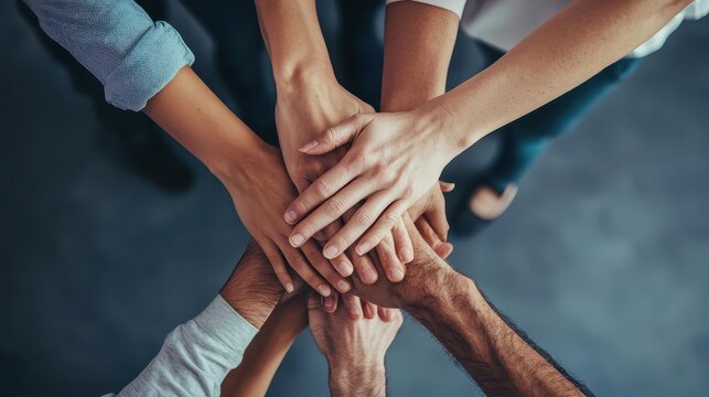 A group of people with their hands together, symbolizing unity and collaboration in a business context, emphasizing teamwork and mutual support.