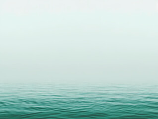 Obraz premium Serene teal water meets a misty sky. A minimalist seascape, perfect for tranquility.