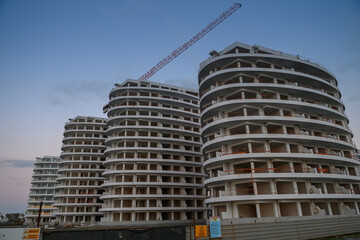 Fototapeta premium Modern architecture of unfinished buildings against twilight sky in a developing urban area