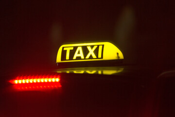 Close-up taxi illuminated sign shines brightly at night, showcasing vibrant red lights in a...