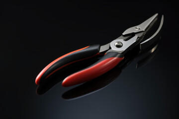 Obraz premium Red and Black Handheld Shears on Reflective Surface, Modern Tool Design