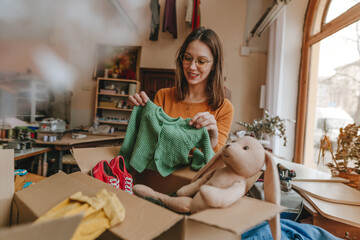Woman sorting an old out-of-use kid clothes and shoes in box