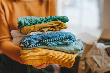 Unrecognizable female volunteer holding clothes collected for charity or converting discarded materials