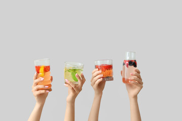 Many hands with infused water on light background