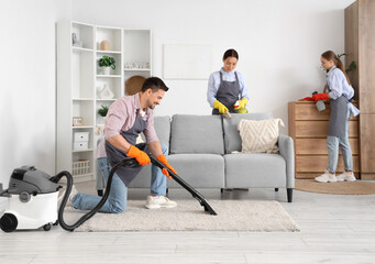 Team of young janitors cleaning in room