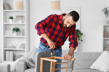 Young man with screwdriver assembling soft bench at home