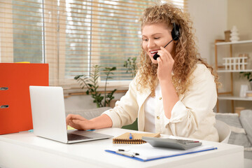 Obraz premium Beautiful young woman with laptop and headset working at home. Freelance concept