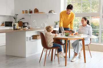 Young man putting Fajita on table at dinner with his family in kitchen