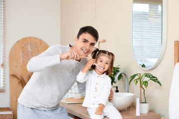 Fototapeta premium Happy father and his cute little daughter brushing teeth in bathroom