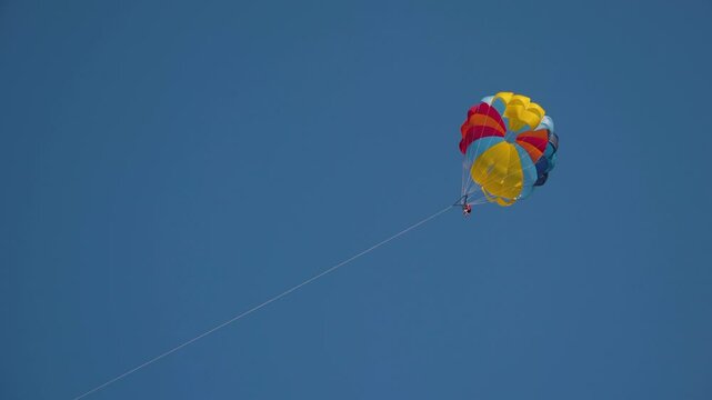 Unrecognizable person enjoying stunning views, creating unforgettable summer memories filled with excitement, freedom, joy that youll cherish for years. Experience exhilarating parasailing adventure