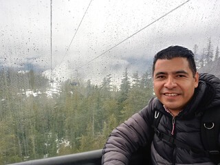 Dark-skinned Latin adult man transports himself in gondola cabin to climb the snowy mountain to do sports and enjoy winter © Arlette