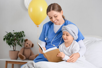 Little girl after chemotherapy with nurse reading book in clinic. Childhood cancer awareness concept