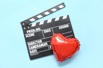 Movie clapper and air balloon in shape of heart on blue background. Valentine's Day celebration